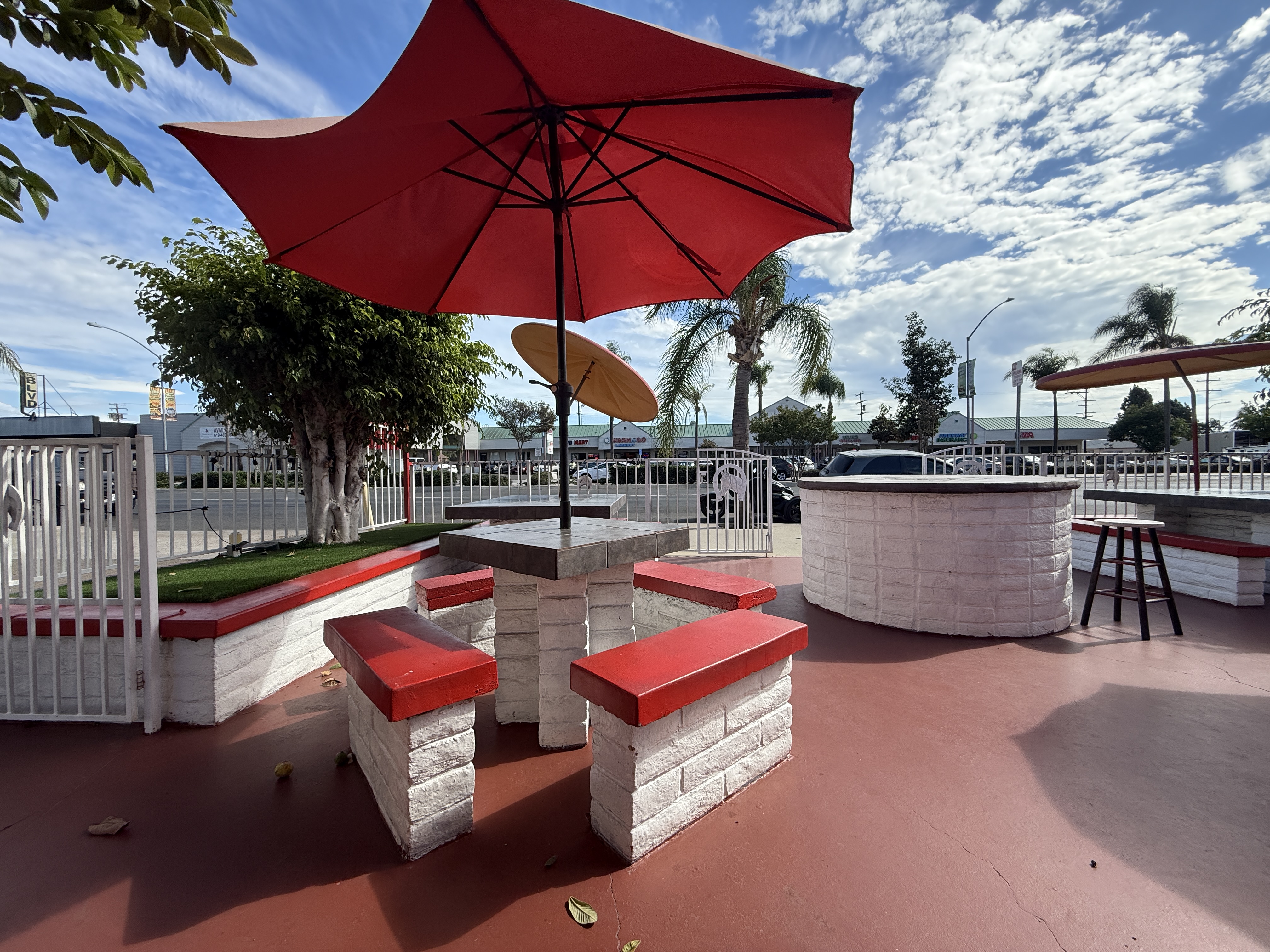 El Rodeo’s outdoor seating with red umbrellas and white brick benches